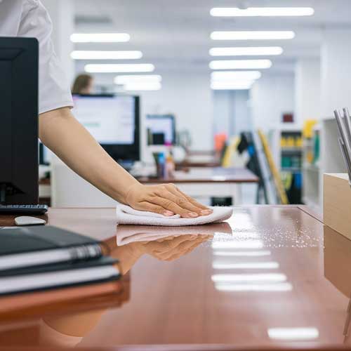 Mano de mujer limpiando con una bayeta la mesa de una oficina. Limpiezas Regueiro es una empresa de limpieza de casas, viviendas. pisos, comunidades, oficinas y empresas ubicada en la provincia de Ourense.