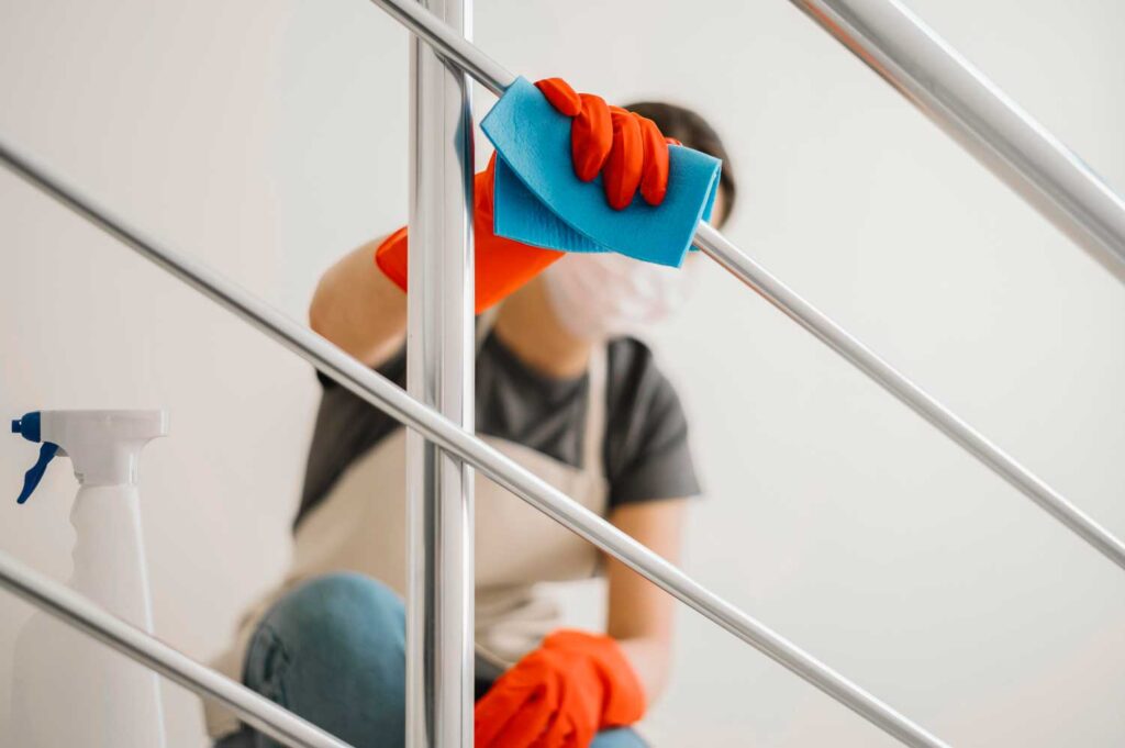 Una profesional de la limpieza limpia la barandilla de las escaleras de una comunidad de vecinos. Limpiezas Regueiro es una empresa de limpieza de casas, viviendas. pisos, comunidades, oficinas y empresas ubicada en la provincia de Ourense.